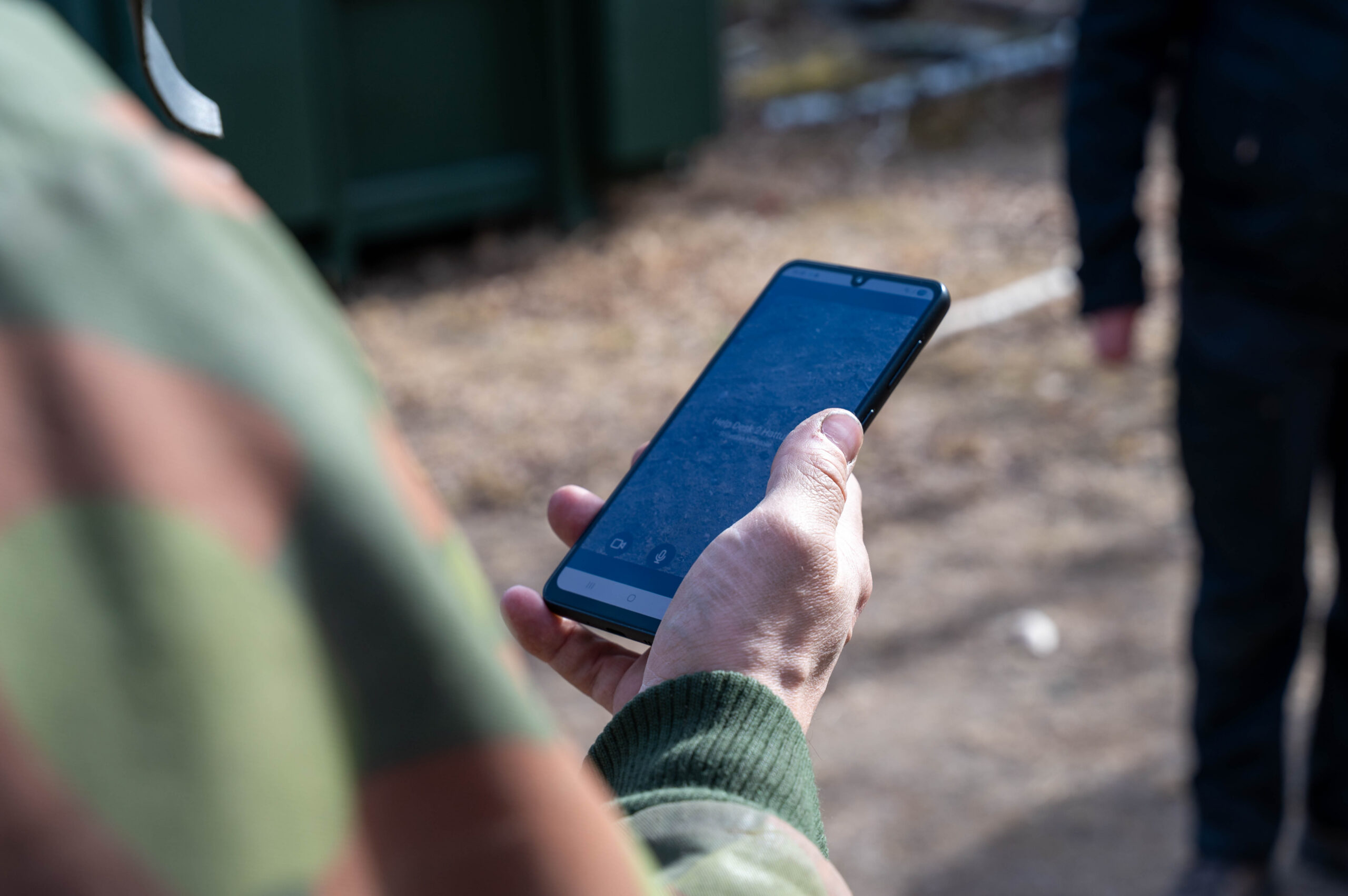 A soldier holding a phone and calling a helpdesk for remote support.